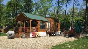 Een houten chalet met een veranda, een overdekte barbecue en een klein terras.