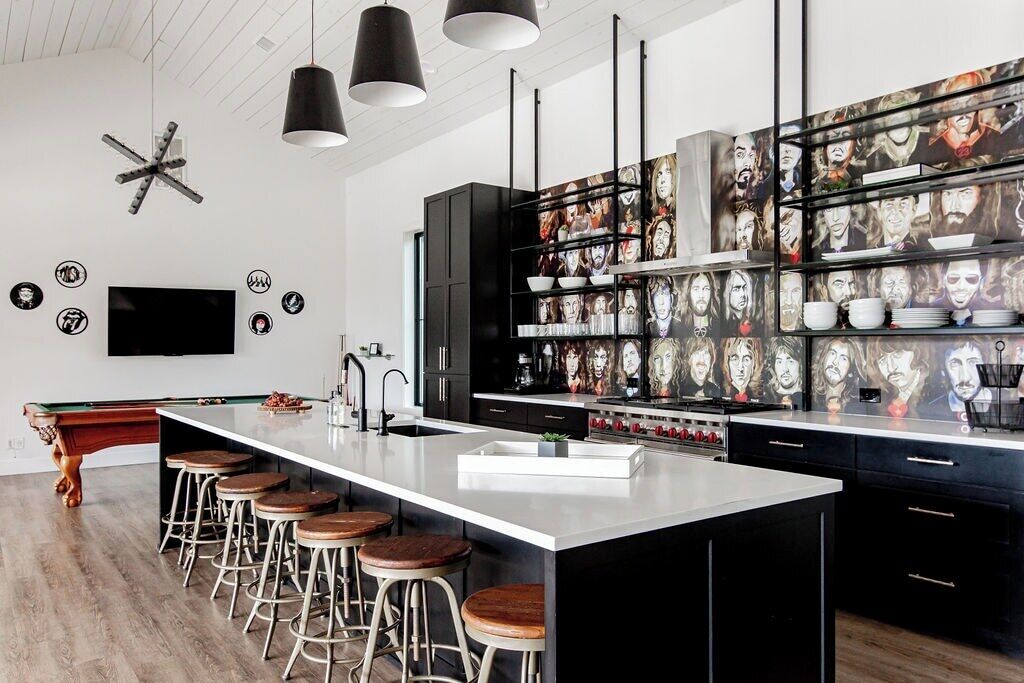 Une cuisine moderne dotée d’un îlot central, de tabourets de bar et d’un téléviseur fixé au mur.