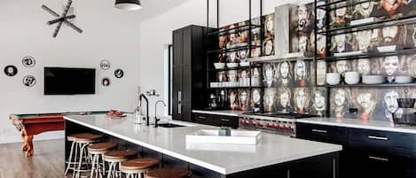 Una cocina moderna con una isla central, taburetes de bar y un televisor montado en la pared.