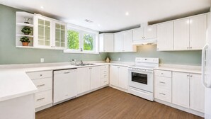 A modern kitchen with white cabinetry, a built-in oven, and a window providing natural light. - Lake Simcoe Waterfront Retreat Near Toronto Private Dock, Sandy Beach  Hot Tub (Georgina)