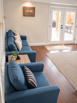 Una sala de estar con un sofá azul, una mesa de centro de madera y un cartel de bienvenida.