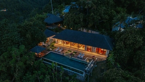 An aerial view of a resort with a swimming pool, multiple guest rooms, and a well-lit outdoor area.
