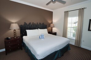 A hotel room with a bed, two bedside tables with lamps, a window with curtains, and a ceiling fan. - Tropical Waters & Sunsets–Beach Club Siesta 106B RVA (Sarasota)