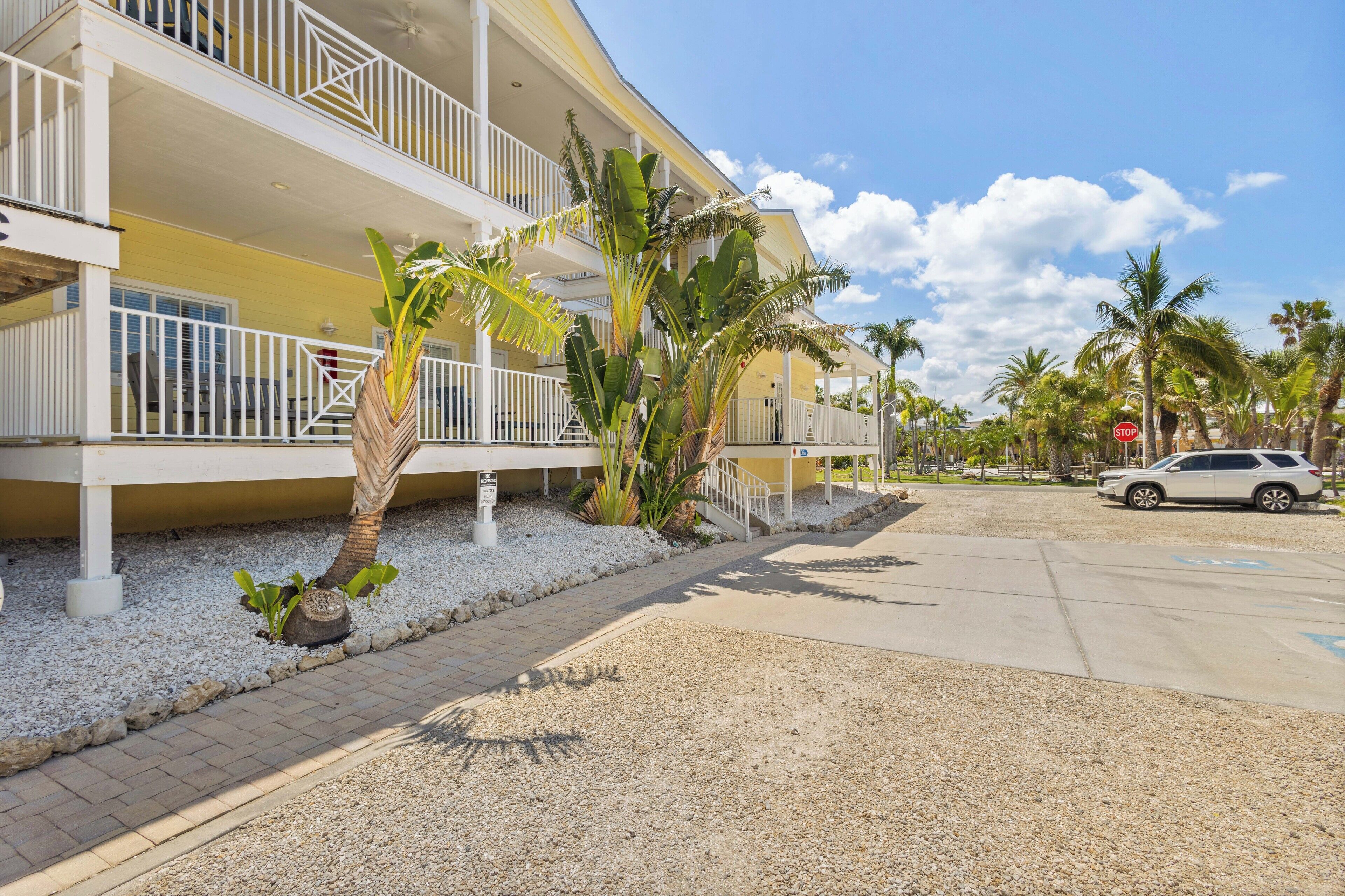 A multi-story hotel with balconies, palm trees, and a parking area.
