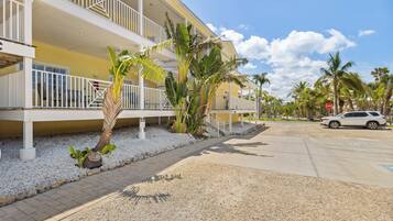 A multi-story hotel with balconies, palm trees, and a parking area.