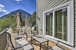 Relax on the deck with a scenic mountain view, featuring a set of chairs and a table.