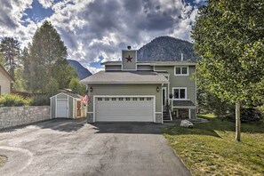 Set amidst lush greenery and a mountain backdrop, this two-story house features a prominent star on the roof and a well-maintained driveway.
