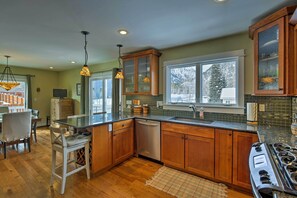 Enjoy cooking in this well-equipped kitchen with a central island, stainless steel appliances, and a large window offering a view of the outdoors.