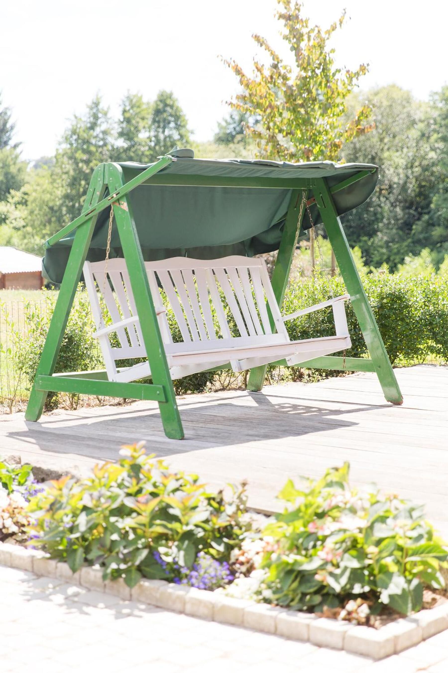 Un columpio verde con asiento blanco en un jardín.
