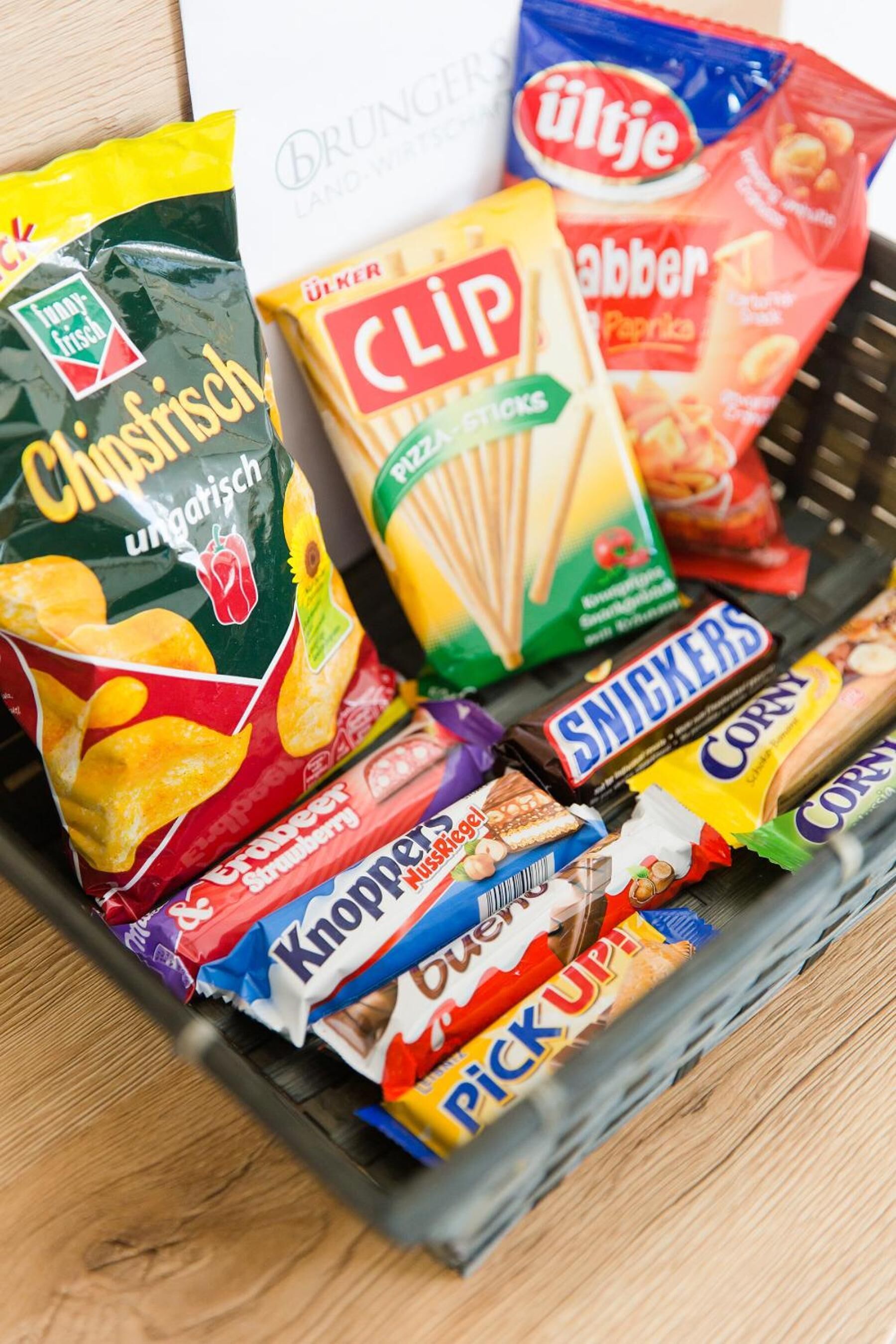 A variety of snack items including chips, a box of clip biscuits, and chocolate bars.