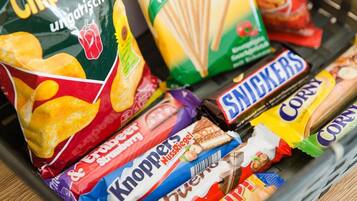 A variety of snack items including chips, a box of clip biscuits, and chocolate bars.