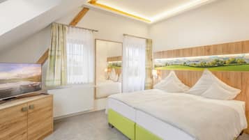 Un dormitorio con una cama, un televisor sobre un mueble de madera, una ventana con cortinas y un cuadro en la pared.