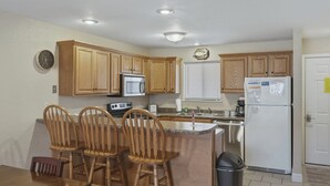 A kitchen with wooden cabinets, a microwave, a toaster, a sink, and a refrigerator.