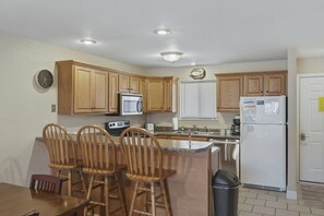 A kitchen with wooden cabinets, a microwave, a toaster, a sink, and a refrigerator.