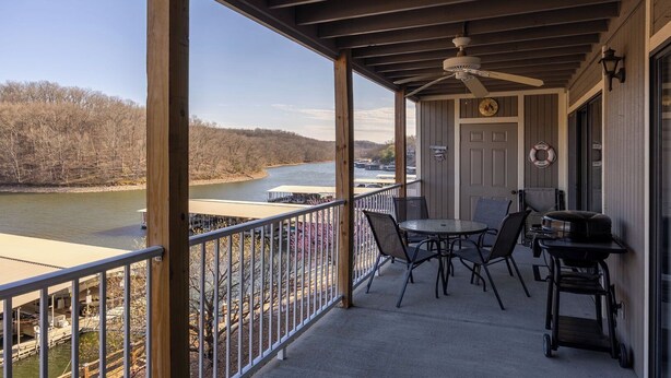 A covered outdoor area with a table and chairs, a ceiling fan, and a view of a river.