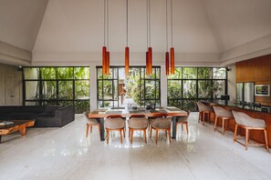 Een ruime woonkamer met een eettafel, stoelen en een bank.