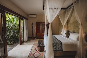 A bedroom with a four-poster bed, a wooden wardrobe, and a large window with a view of greenery.