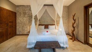 A bedroom with a four-poster bed, a wooden table, and a stone wall. - Ubud Villa - 4BR Jungle View (Ubud)