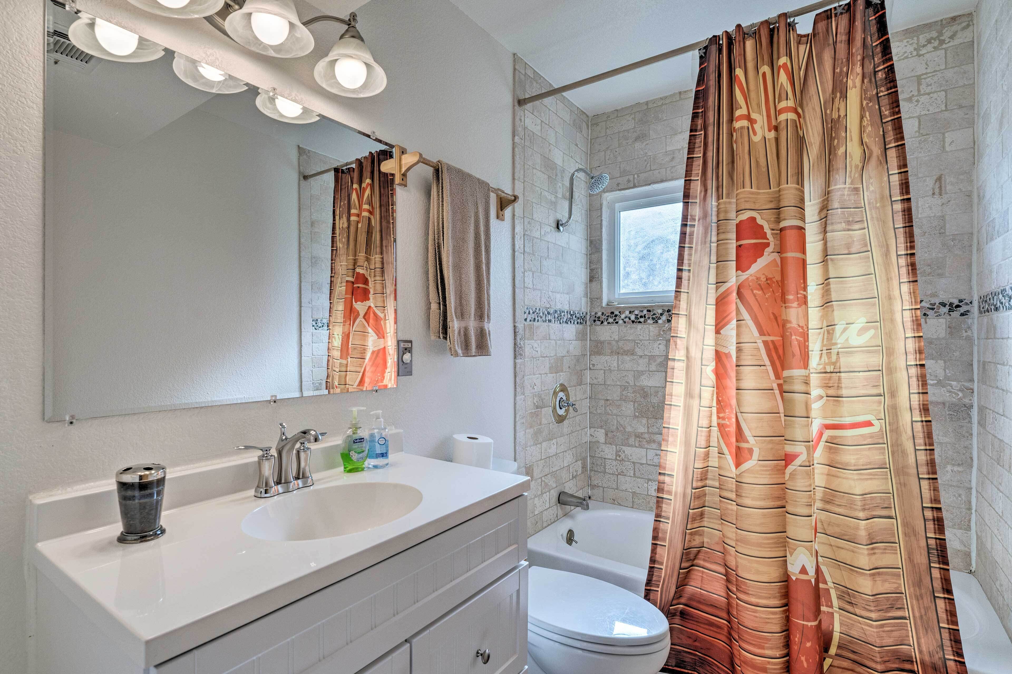 Un baño con lavamanos blanco, espejo y cortina de ducha con diseño geométrico.