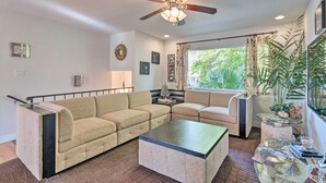 Un salon avec un canapé beige, une table basse en verre et un ventilateur de plafond.
