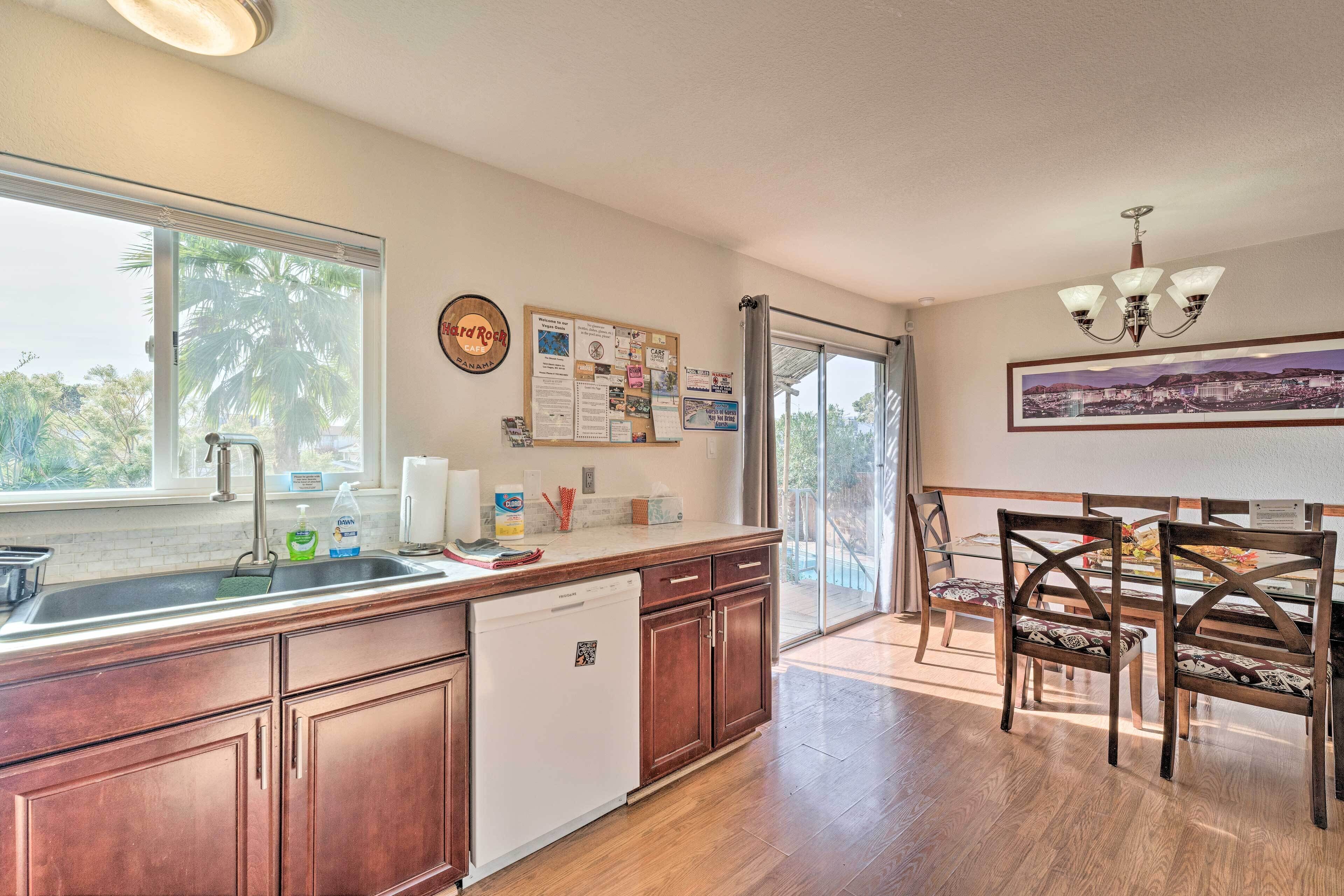 A kitchen with a dishwasher, a dining area with chairs, a view of palm trees, and a Hard Rock Cafe sign.