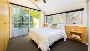 A modern bedroom with a large bed, sliding glass doors to a balcony, a ceiling fan, and a wooden shelf with towels. - Nine Steps - private estate on 29 acres with stunning views of Mount Buffalo (Porepunkah)