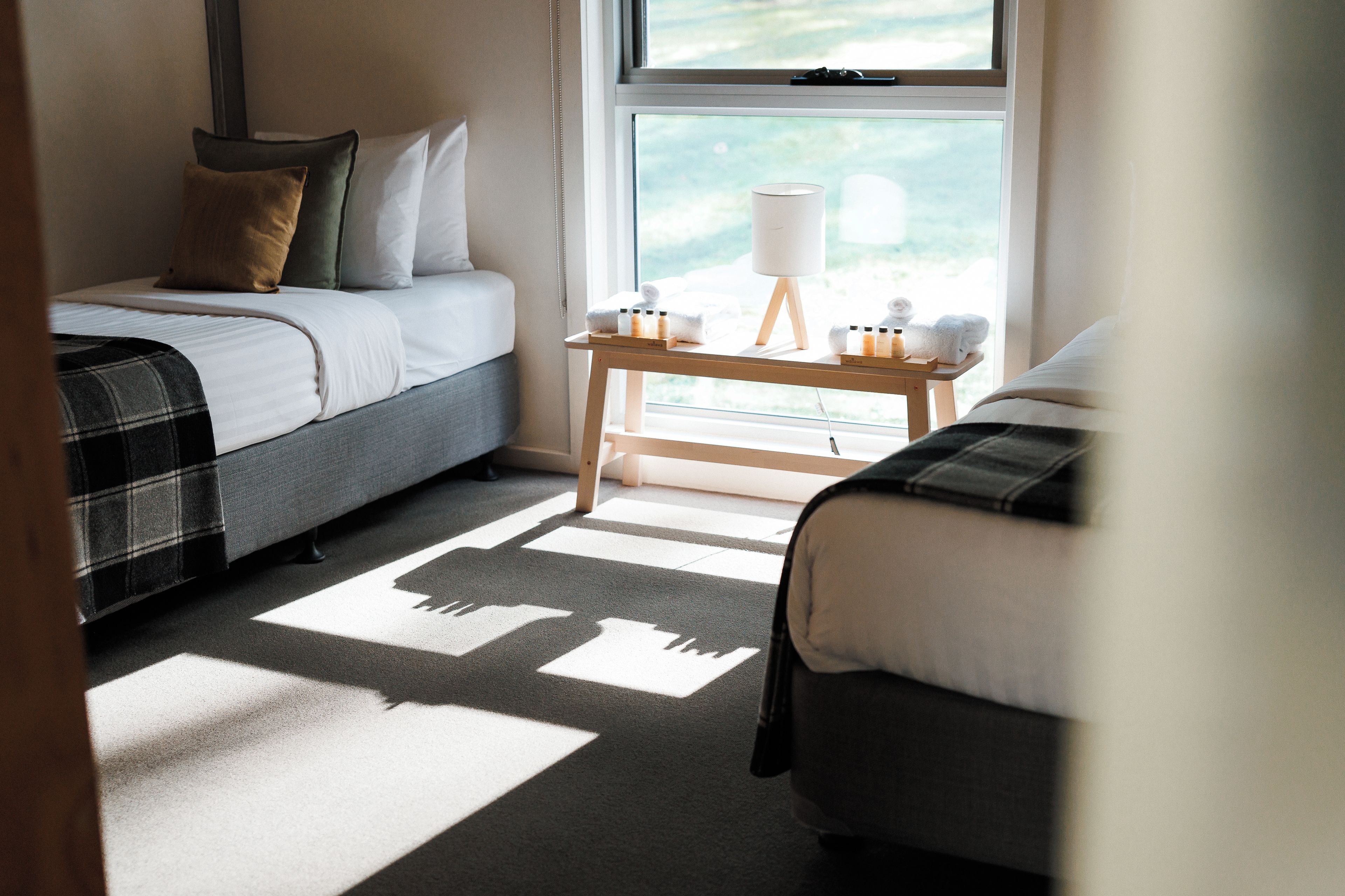 Una camera da letto con due letti, un comodino con articoli da toilette e una finestra con vista.