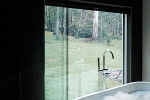 Un baño con un ventanal que ofrece vistas a una zona boscosa.