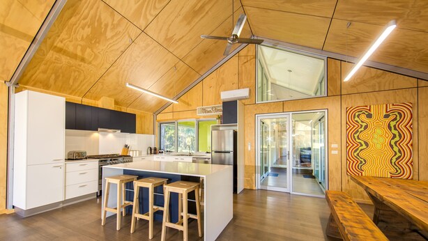 A modern kitchen with wooden ceiling, a central island with stools, and a dining area with a bench. - Nine Steps - private estate on 29 acres with stunning views of Mount Buffalo (Porepunkah)