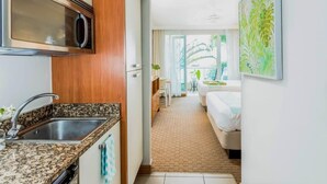 Una habitación de hotel moderna con cocina, una mesa de comedor y un balcón con vistas.