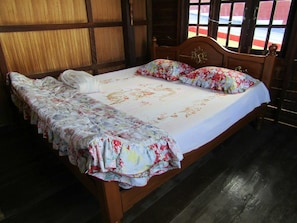 Una cama de madera con ropa de cama floral y una almohada blanca.