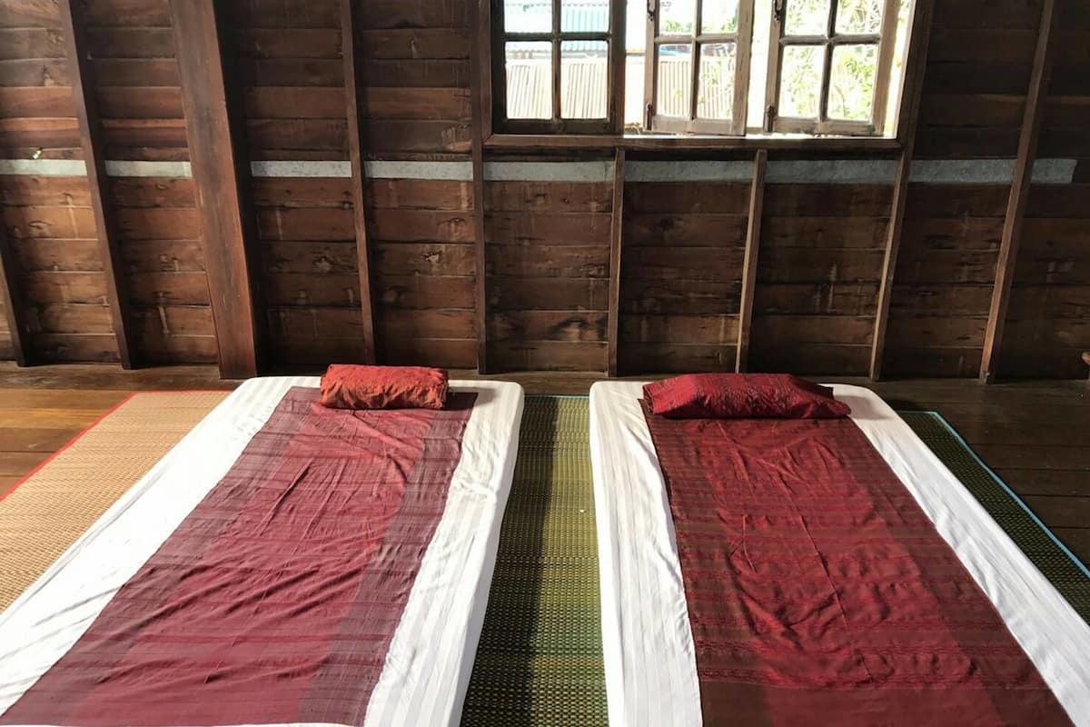 Deux lits simples avec des couvertures rouges dans une pièce en bois dotée d’une fenêtre.
