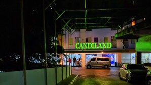 Un edificio con un letrero de neón que dice "CANDILAND" y un estacionamiento con coches.