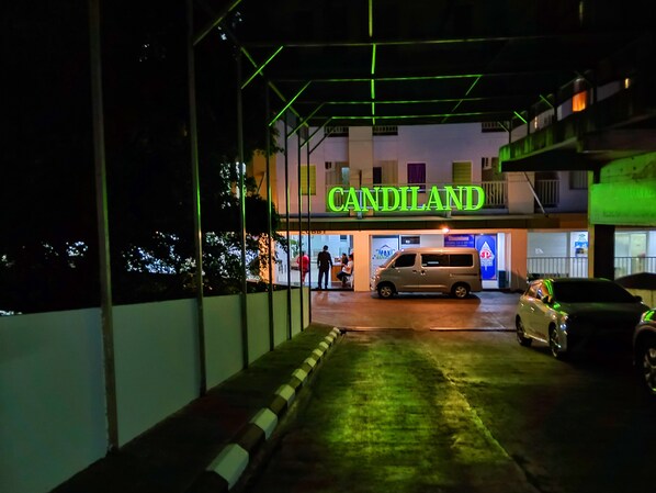 A building with a neon sign reading "CANDILAND" and a parking area with cars.