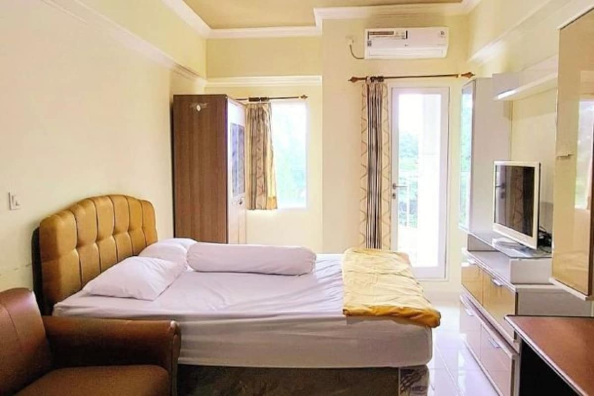 A hotel room with a bed, a TV, a wardrobe, and a window with curtains.