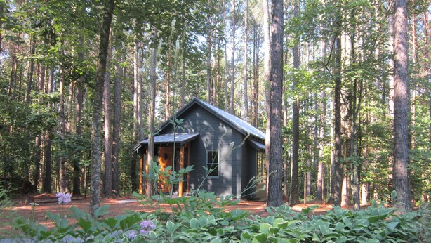 Una cabaña rodeada de árboles altos en un bosque.