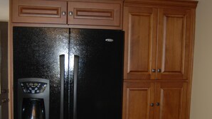 Una cocina con un refrigerador negro, armarios de madera y una cafetera.