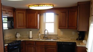 Una cocina con armarios de madera, estufa, lavavajillas y ventana.