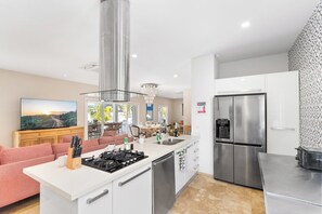 Cocina moderna con una isla central, electrodomésticos de acero inoxidable y un comedor con vistas.