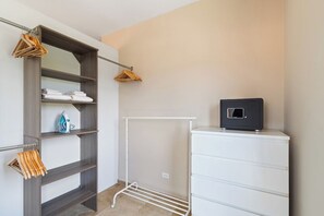 Ett rum med en garderob, ett torkställ och ett litet skåp.