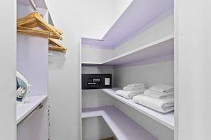 Ein begehbarer Kleiderschrank mit Regalen für gefaltete Kleidung, einer Kleiderstange und einem Bedienfeld.