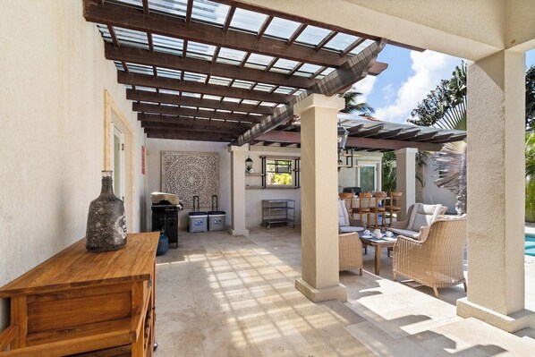 Eine Außenpatio-Terrasse mit Pergola, Sitzgelegenheiten, einem Pool und einer Bar.