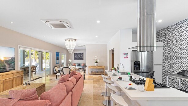 A modern kitchen with a central island, stainless steel appliances, and a chandelier. - Upscale 5BR Villa: Game Room, Private Pool, Patio (Noord)
