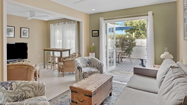 A living room with a television, sofa, and a wooden chest. There is a dining area with chairs and a table.