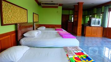 A hotel room with three beds, a television, and a kitchenette.