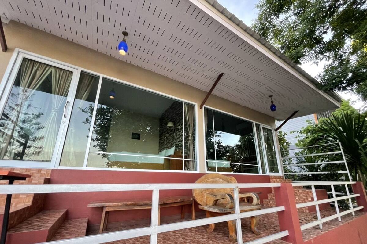 A two-story building with a balcony, large windows, and a wooden bench.