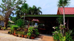 A covered outdoor area with potted plants and a sign. - Techno Riverview Resort (Kamphaeng Phet)