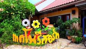 A garden with a stone pathway, potted plants, and a house with a tiled roof. - Techno Riverview Resort (Kamphaeng Phet)