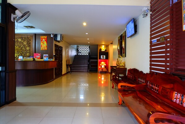 Un vestíbulo de hotel con mostrador de recepción, una escalera y una zona de estar.
