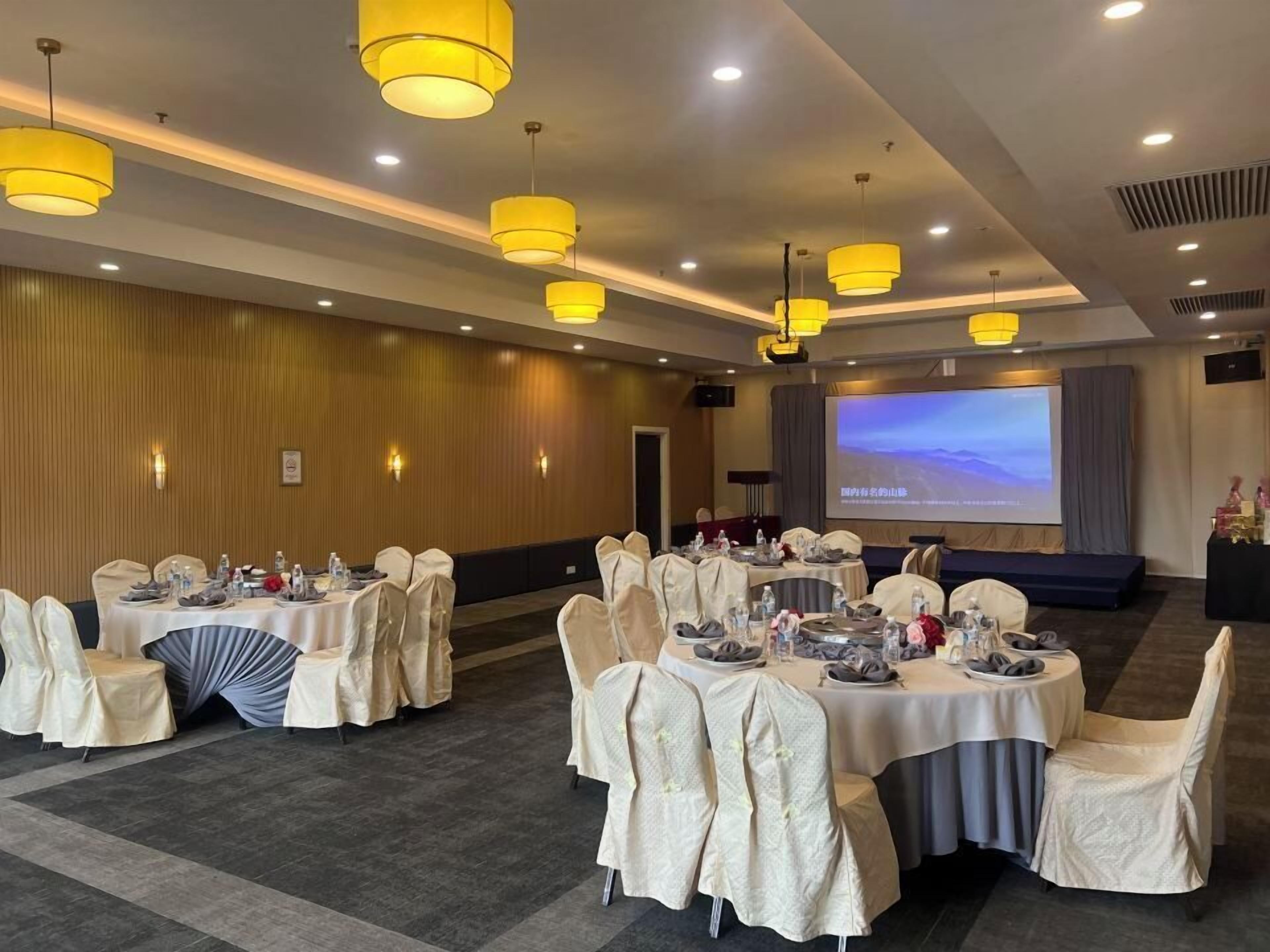 A conference room with round tables, chairs, and a large screen for presentations.